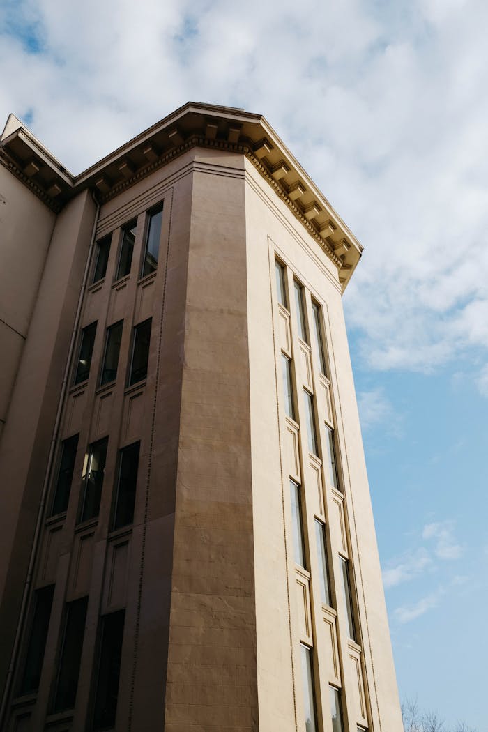 Low angle view of a modern urban building against a partly cloudy sky.